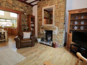 a living room with a brick fireplace and a chair at Whitfield Cottage 21 Silver Street in Wolsingham