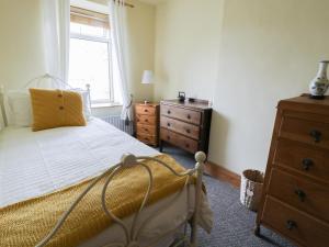 Whitfield Cottage 21 Silver Street في Wolsingham: غرفة نوم بسرير وخزانة ونافذة