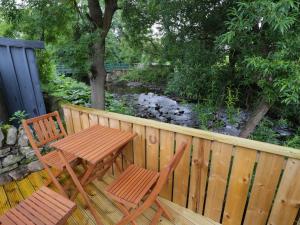 a wooden table and chairs on a wooden deck with a stream at Whitfield Cottage 21 Silver Street in Wolsingham