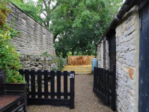 a black fence next to a stone wall with a bench at Whitfield Cottage 21 Silver Street in Wolsingham +3 photos