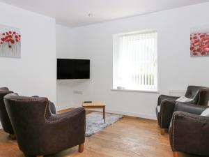 a living room with chairs and a flat screen tv at Witchelm House in Inverness