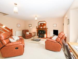 a living room with leather furniture and a fireplace at The Farm Steading in Aberlour