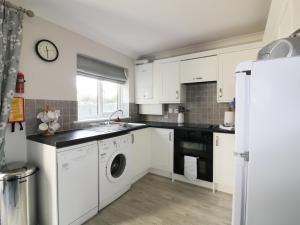 a kitchen with white cabinets and a washer and dryer at Gull Cottage in Padstow