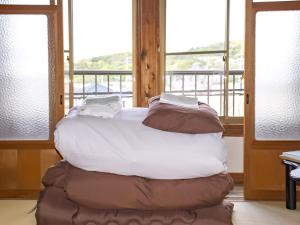 a bed sitting in a room with windows at Guest Cafe Kuchikumano in Kamitondacho