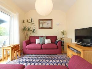 a living room with a red couch and a tv at Parula in St Just