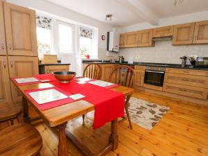 a kitchen with a wooden table with a red table cloth at Upper Highlees Farm in Luddenden Foot