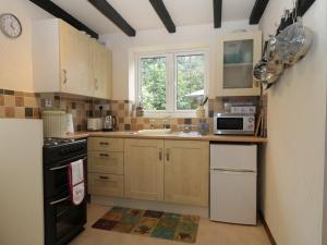 cocina con fregadero y microondas en Mrs Dale's Cottage, en Clenchwarton