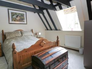 um quarto com uma cama de madeira e uma grande janela em Mrs Dale's Cottage em Clenchwarton