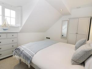a white bedroom with a bed and a dresser at Chine Cottage in Sandsend