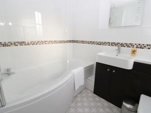 a white bathroom with a tub and a sink at Chine Cottage in Sandsend +29 photos