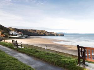 two benches sitting on the side of a beach at Chine Cottage in Sandsend