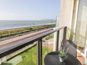 a balcony with a table and a view of the beach at 12 West End Point in Pwllheli