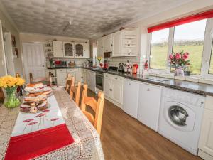 a kitchen with a table and a kitchen with a dishwasher at Tyn Y Gorlan in Brynkir