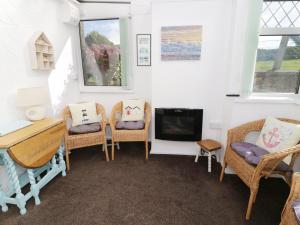 a living room with chairs and a desk and a tv at Trigfa Cottage in Abersoch