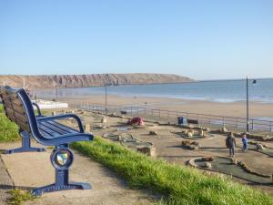 a blue bench sitting on the side of a beach at Coastal Cottage in Reighton