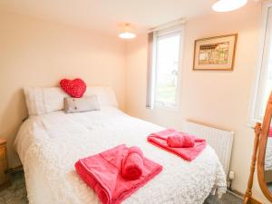 a bedroom with pink towels on a white bed at Y Caban Clyd in Morfa Nefyn