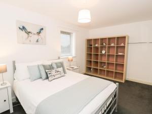 een slaapkamer met een wit bed en een boekenplank bij 7 Marina View in Pwllheli
