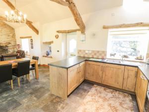 a kitchen with wooden cabinets and a table and a dining room at Yr Hen Dy in Ffestiniog