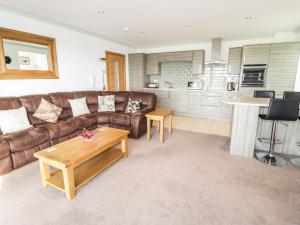 a living room with a brown couch and a table at 2 Y Bae in Trearddur