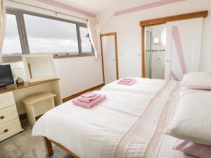 a bedroom with two beds with pink towels on them at 2 Y Bae in Trearddur