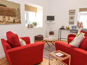 sala de estar con 2 sillas rojas y chimenea en The Turkey House en Foulden