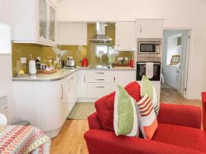 a living room with a red couch and a kitchen at The Turkey House in Foulden