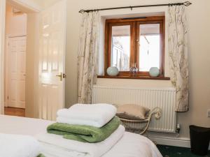 1 dormitorio con cama, ventana y silla en Clun Forest Cottage en Monkhopton