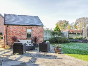 a patio with two chairs and a brick house at Clun Forest Cottage in Monkhopton
