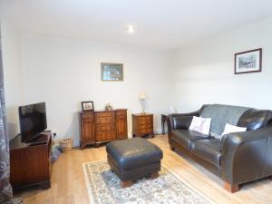 a living room with a leather couch and a tv at The 'Stables' in Waterfall