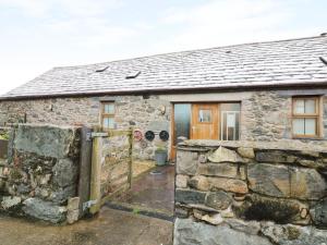 una antigua casa de piedra con una puerta y una pared de piedra en Beudy Mawr, en Llanddeiniolen