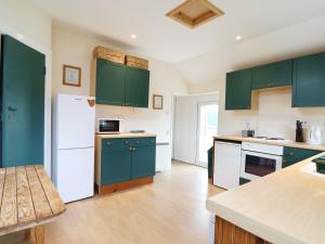 eine Küche mit grünen Schränken und einem weißen Kühlschrank in der Unterkunft Kerrisdale in Dornoch