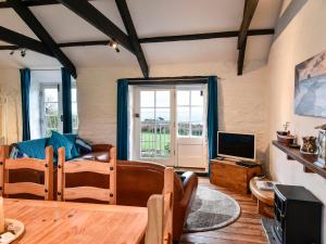 uma sala de estar com uma mesa e uma televisão em Threshings Cottage em Tintagel