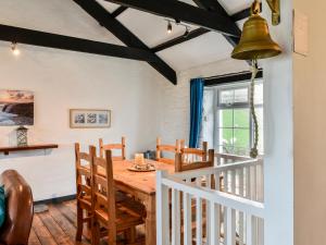 uma sala de jantar com uma mesa de madeira e cadeiras em Threshings Cottage em Tintagel