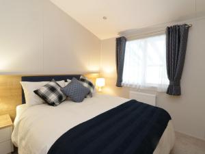1 dormitorio con cama con almohadas y ventana en Woodstock Lodge, en Skelmorlie