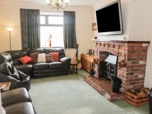 a living room with a couch and a fireplace at Wrens Nest in Coreley
