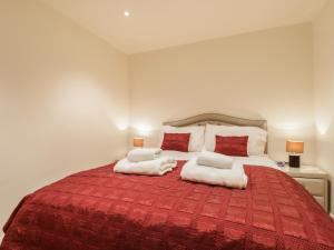 um quarto com uma grande cama vermelha e 2 almofadas em Wrenville em Keswick