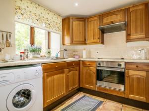 a kitchen with wooden cabinets and a washer and dryer at Rosegarth Cottage in Morland