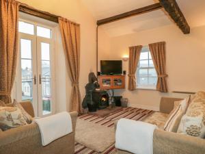 a living room with two couches and a tv at Ale Cottage in Ireby