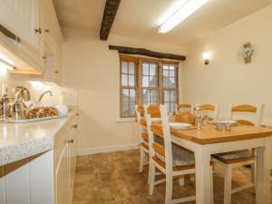 a kitchen with a wooden table and a dining room at Ale Cottage in Ireby