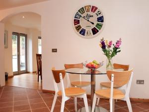 a dining room with a table and a clock on the wall at Cross Syke Barn in Shirwell