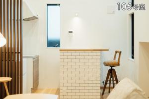 uma cozinha com um banco ao lado de uma lareira de tijolos em YOUR ROOM 熊本駅 em Kumamoto