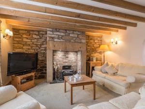 a living room with a stone fireplace and a television at Fisherman's Cottage in Seahouses