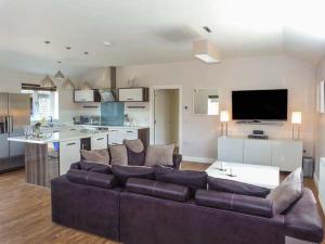 a living room with a brown couch and a kitchen at Willow Lodge in Canterbury