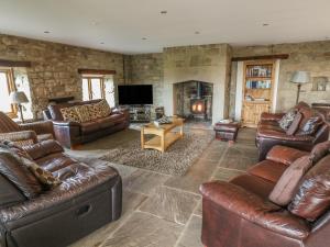 uma sala de estar com mobiliário de couro e uma lareira em Swallow Barn em Keighley