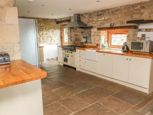 uma cozinha com armários brancos e uma parede de pedra em Swallow Barn em Keighley