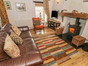 a living room with a leather couch and a wood stove at Rosemary Cottage in Carnforth