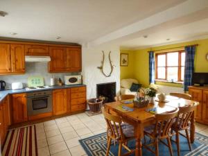 une cuisine avec une table et des chaises en bois ainsi qu'une cuisine avec une cuisinière dans l'établissement Kingsley Cottage, à Hickling 4 autres photos
