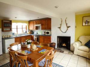 a kitchen with a table and chairs and a fireplace at Kingsley Cottage in Hickling