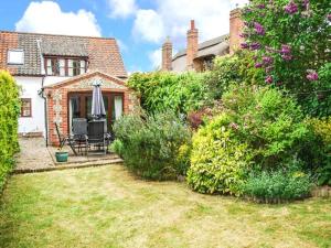 une maison avec une cour dotée d'une chaise et d'un parasol dans l'établissement Kingsley Cottage, à Hickling