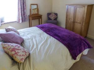 Un dormitorio con una manta morada en una cama en Bobbin Cottage en Matlock